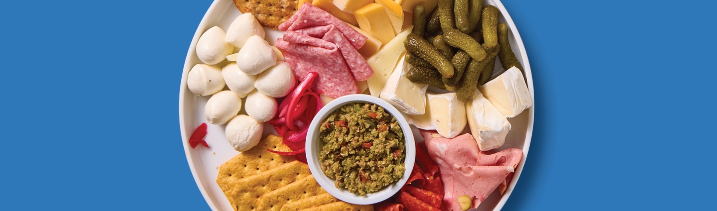 Charcuterie board with assorted crackers, deli meats, fresh cheeses.