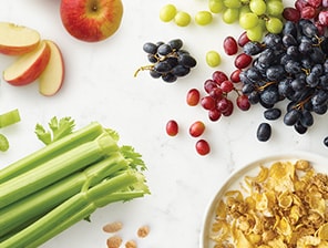 Celery bunch, apple, grapes, and bowl of grain cereal