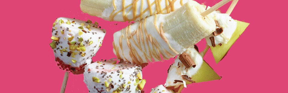 Assorted fruits dipped in yogurt and sprinkled with assorted toppings