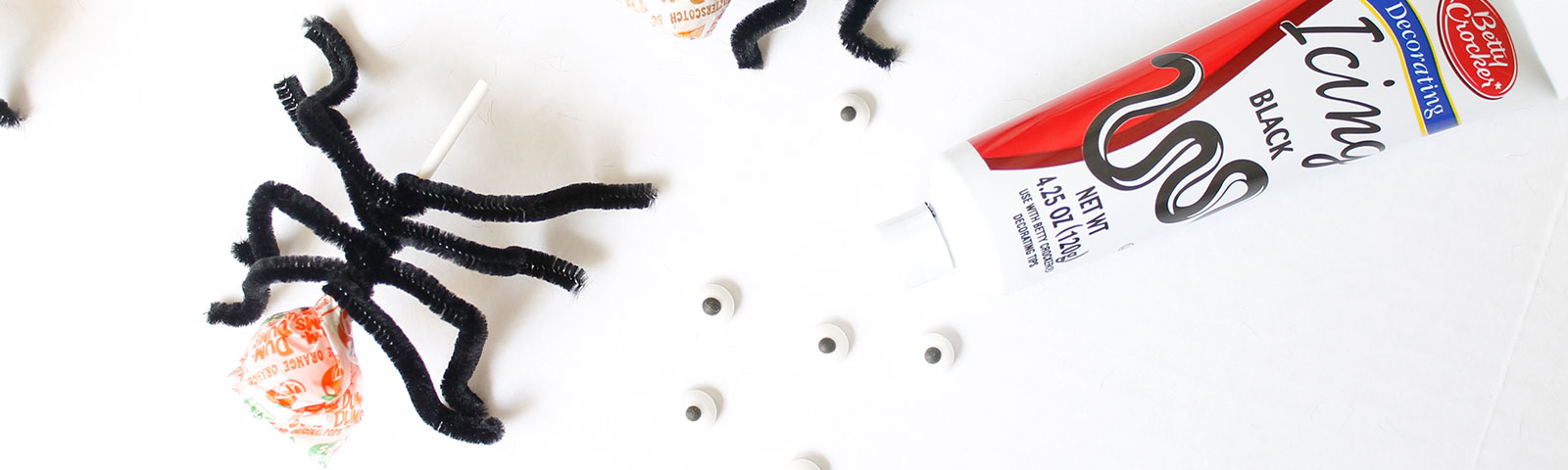 DIY spider suckers with black pipe cleaners attached to lollipops
