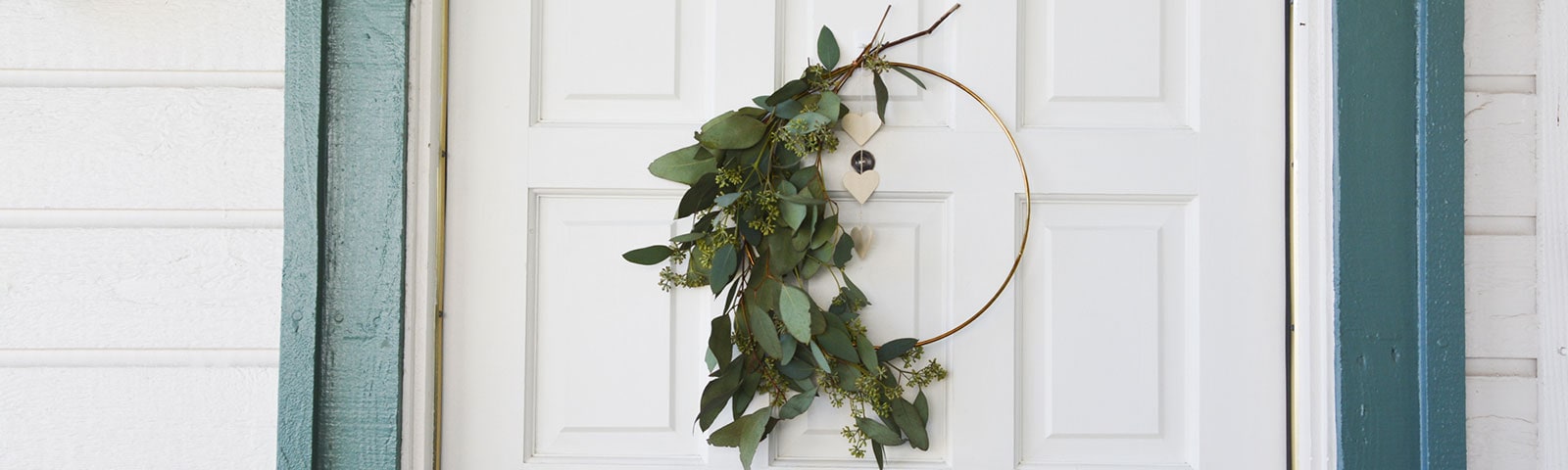 A white door with a handcrafted eucalyptus wreath hanging in the center