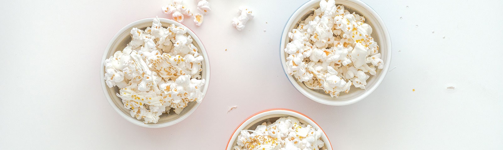 Three bowls of popcorn topped with edible glitter sprinkles