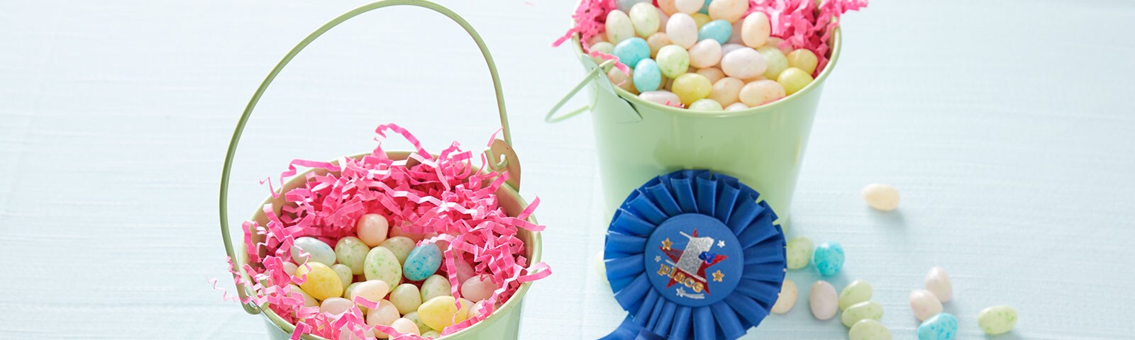 Green baskets filled with jelly beans and pink crinkle paper with a blue "first place winner" ribbon on the side