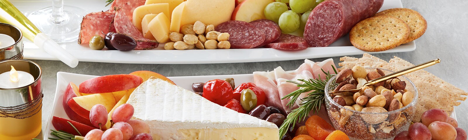 Meat and cheese platters on a table next to a flameless candle